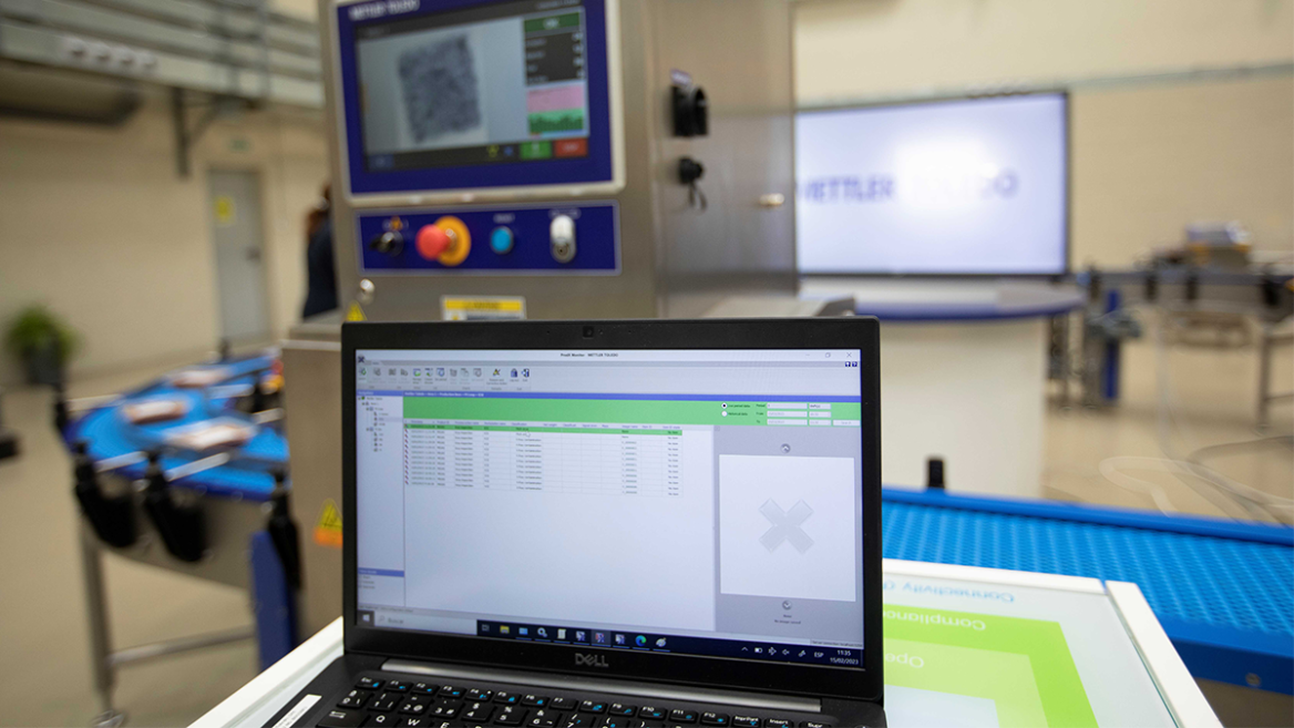 A close-up of a laptop displaying software used to control or monitor a production line. The image conveys a sense of a modern, digitally monitored production environment.