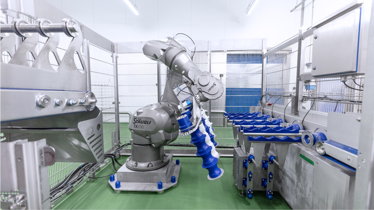 Another robot is mounted on a movable arm and features blue and white components. The robot appears to be performing packaging or inspection tasks. The facility looks modern and technologically advanced.