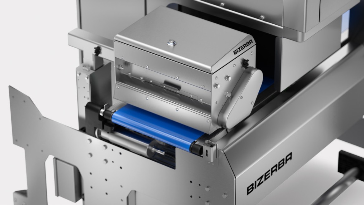 View into the interior of a highly automated industrial machine, with a central component labeled "Bizerba." The part is mounted on a blue conveyor roller, the entire construction is made of stainless steel, suggesting a sterile environment typical for food processing.