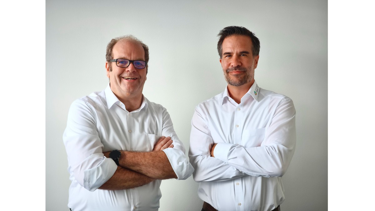 Two people wearing white shirts with rolled-up sleeves are working together at the machine in a professional environment