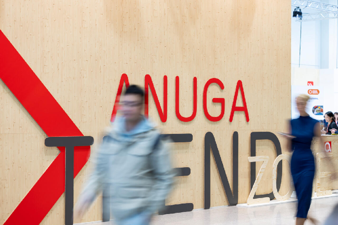Two people walking past a wall with the inscription Anuga Trend Zone - symbolic for food innovations at Anuga 2025