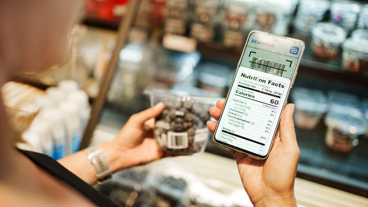 Eine Frau scannt ein Produkt und sieht auf ihrem Smartphone die entsprechenden Inhalttstoffe des Produkts