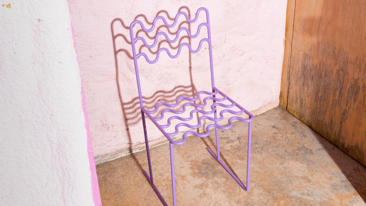 A modern chair made from thin, winding metal in soft purple stands in a room with a raw floor. The seat and backrest are wave-shaped and open-worked. In the background, there is one wall painted pale pink and another with a natural, untreated wood surface. The chair's shadow is cast onto the wall, indicating overhead lighting.