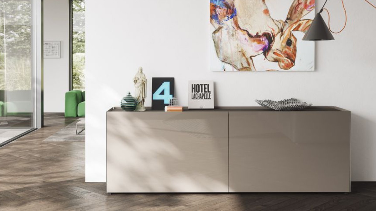 Minimalist white-gray sideboard with decor. Background shows a window and green seating. Bespoke furniture by Kettnaker. Photo: Kettnaker 