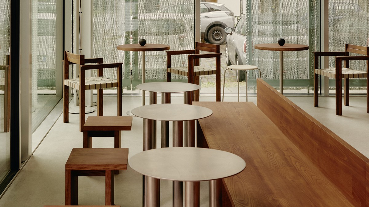 Interior featuring simple wooden chairs and metal tables in a café-like setting.