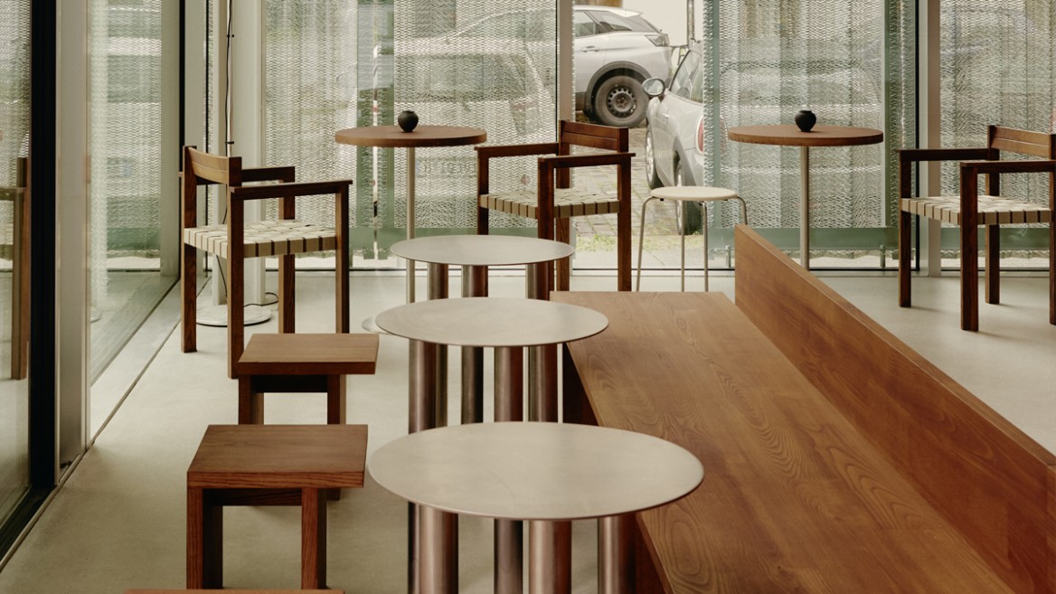 Interior featuring simple wooden chairs and metal tables in a café-like setting.