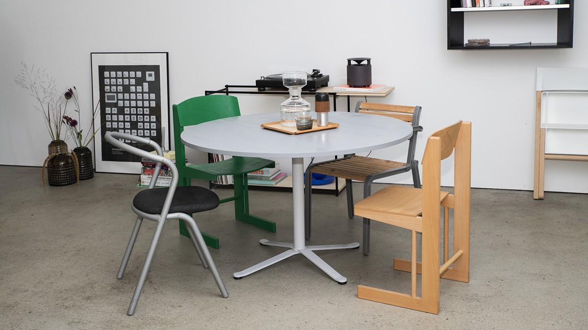 Interior featuring minimalist furniture, including a round table and contrasting chairs made of different materials.