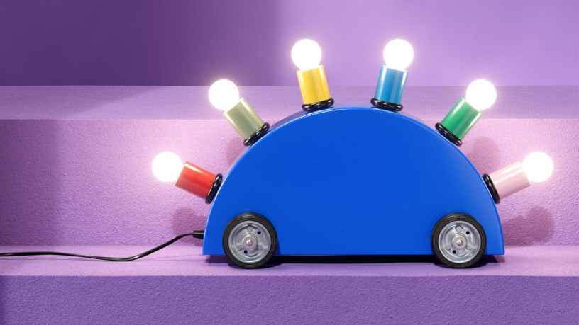 Lamp shaped like a blue toy car with colorful light bulbs on a purple background.