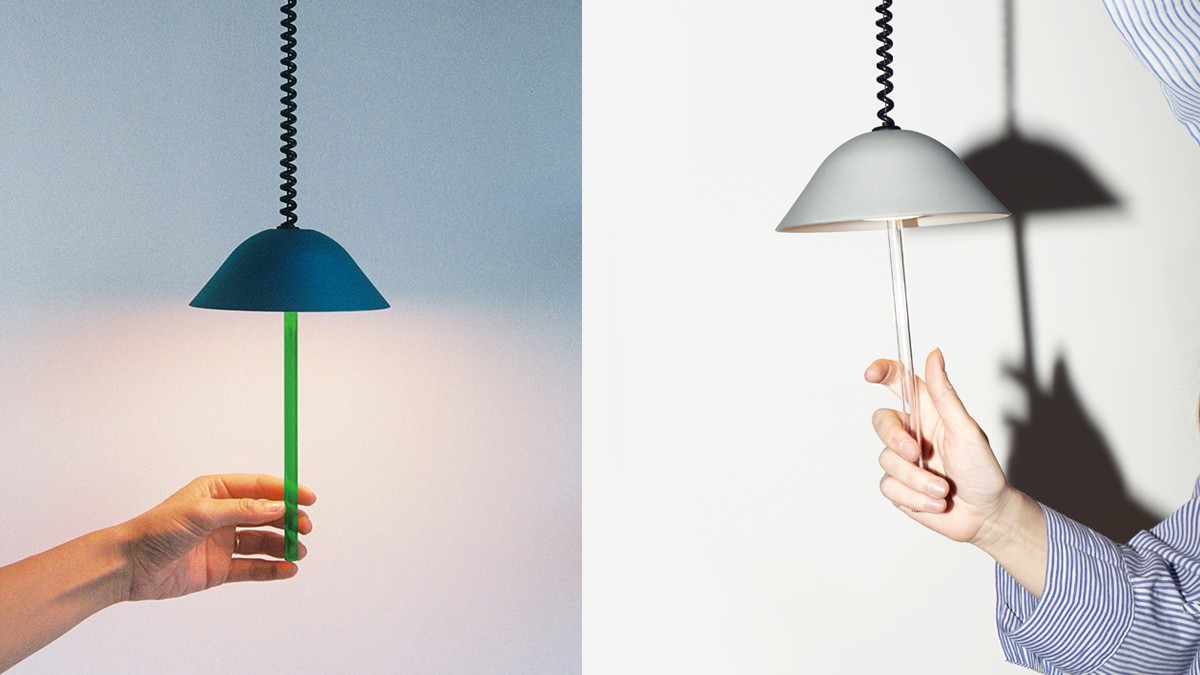 Two minimalist pendant lamps with a semicircular shade, each being touched by a hand.