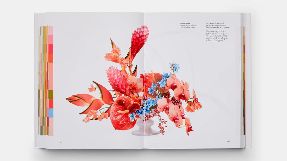 Double-page spread of a design book with a colorful floral arrangement and color scale on the side.