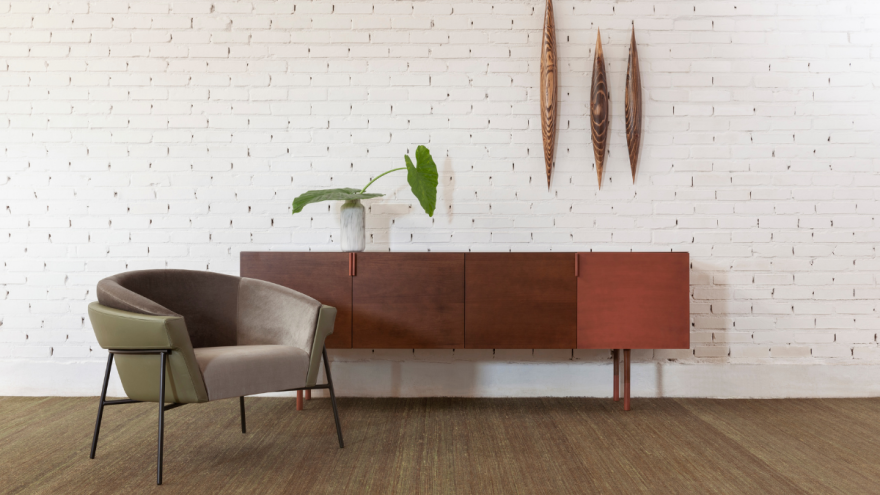 Sideboard in dunkelbraunem Holz mit Sessel im Vordergrund Sideboard in dunkelbraunem Holz mit Sessel im Vordergrund