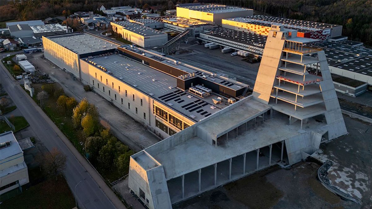 Aerial view of a large industrial and production complex with a distinctive tower structure.