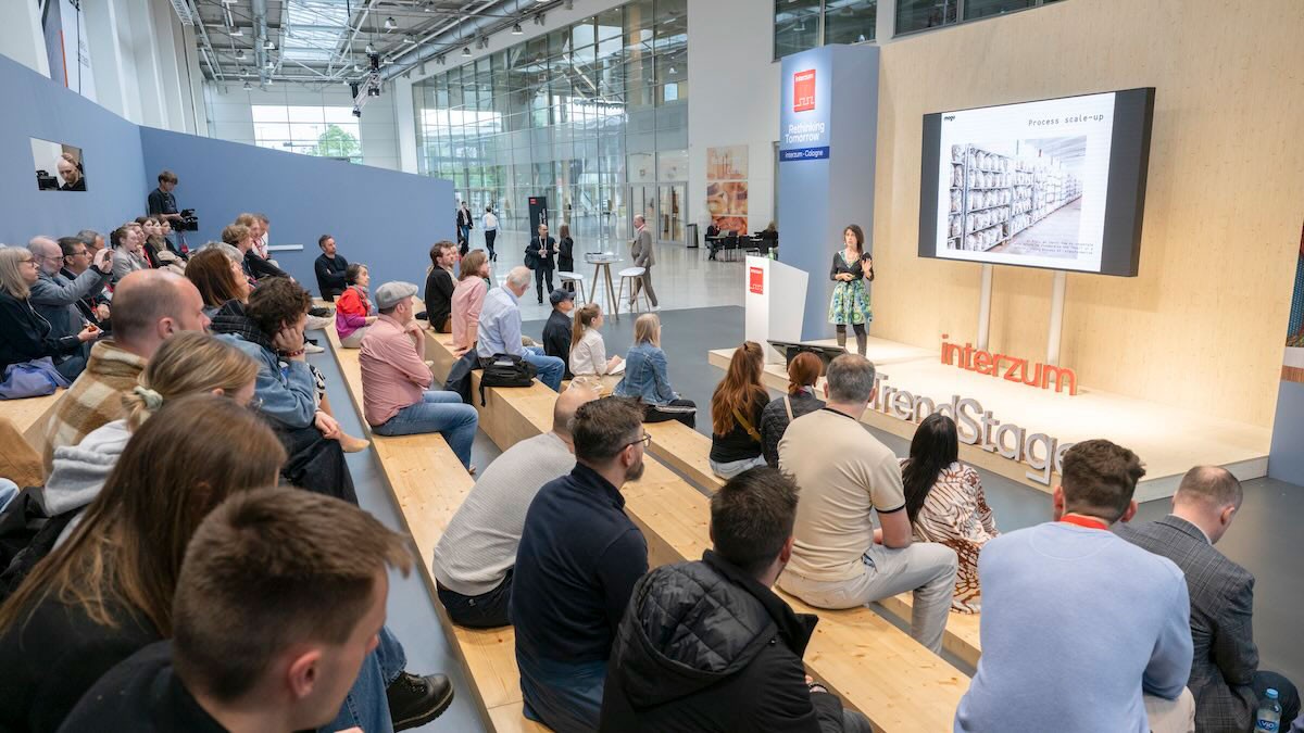  Audience attending a presentation at the interzum Trend Stage in an exhibition hall.