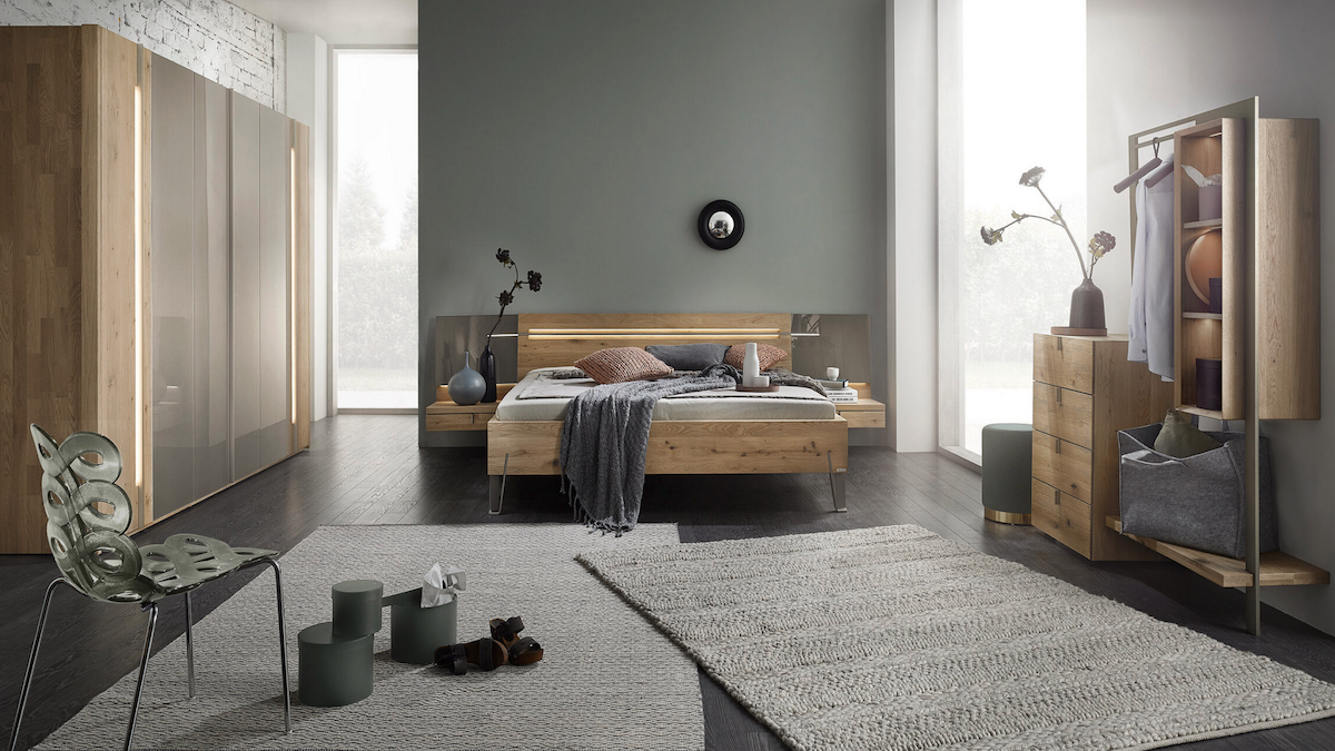 A spacious bedroom with plenty of room, brown wooden furniture, and gray walls