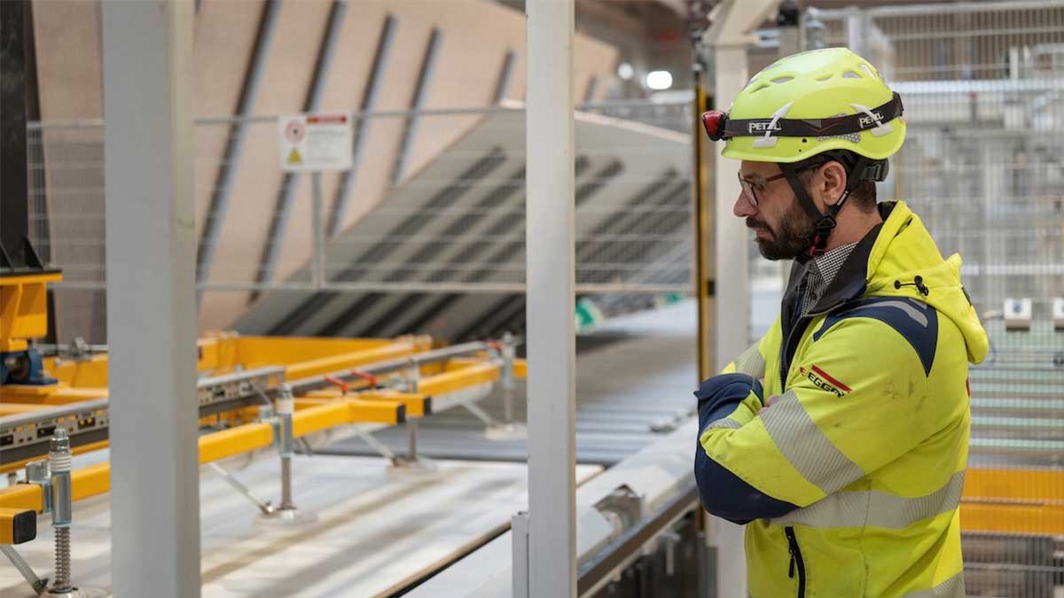 Worker monitors automated short-cycle press for coating decorative wood panels in a modern production facility