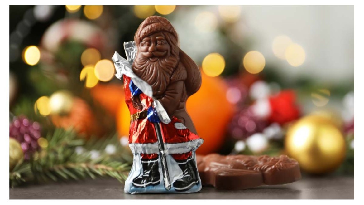 Unwrapped chocolate Santa in front of Christmas decorations - symbolic for seasonal sweets at Christmas.