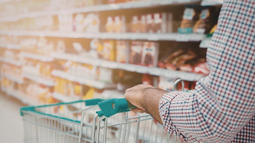 A person pushing a shopping trolley through the supermarket - representative for retail listings.