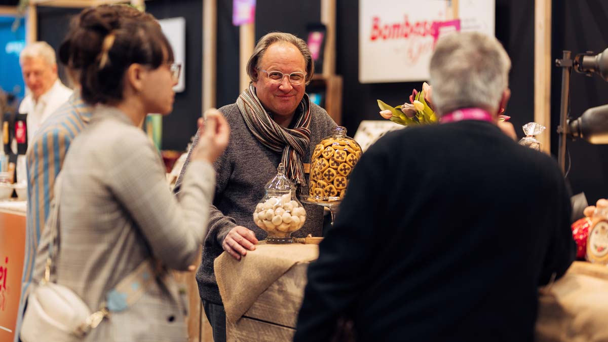 Group of people standing in front of a silver machine, a man in a white coat explaining something