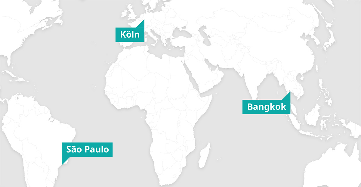 Eine Weltkarte zeigt die Lage von drei Städten mit blauen Etiketten: Köln in Europa, Bangkok in Südostasien und São Paulo in Südamerika. Die Beschriftungen heben die Städte deutlich hervor und sollen ihre weltweite Verortung verdeutlichen.