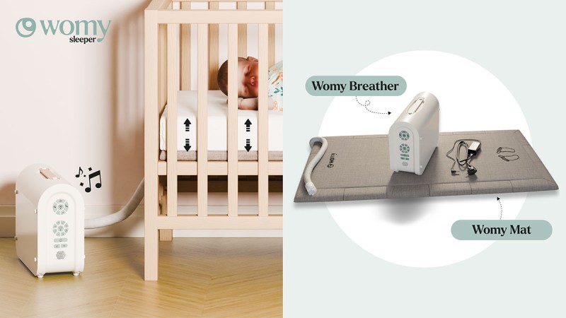 Womy Sleeper baby monitor device placed next to a wooden crib with a beige mattress and a woven rug underneath
