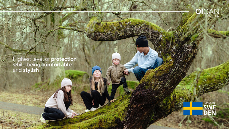 Family wearing Oican Wear safe hats sitting and standing on a large moss-covered tree in a forest, promoting protection, comfort, and style