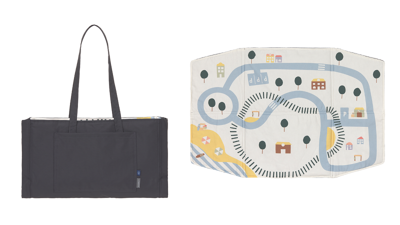 Laessig black rectangular tote bag with long handles next to a play mat featuring roads, trees, and buildings