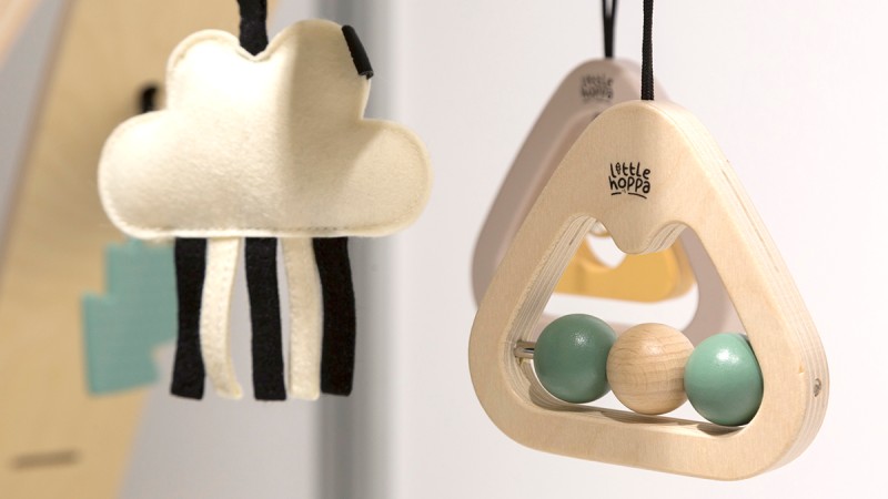 Two hanging accessories for children: a felt cloud with black stripes and a wooden accordion with colorful beads. Both hang side by side.