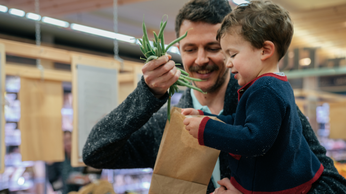 Father and son buy fresh organic-labelled vegetables at the grocery store.