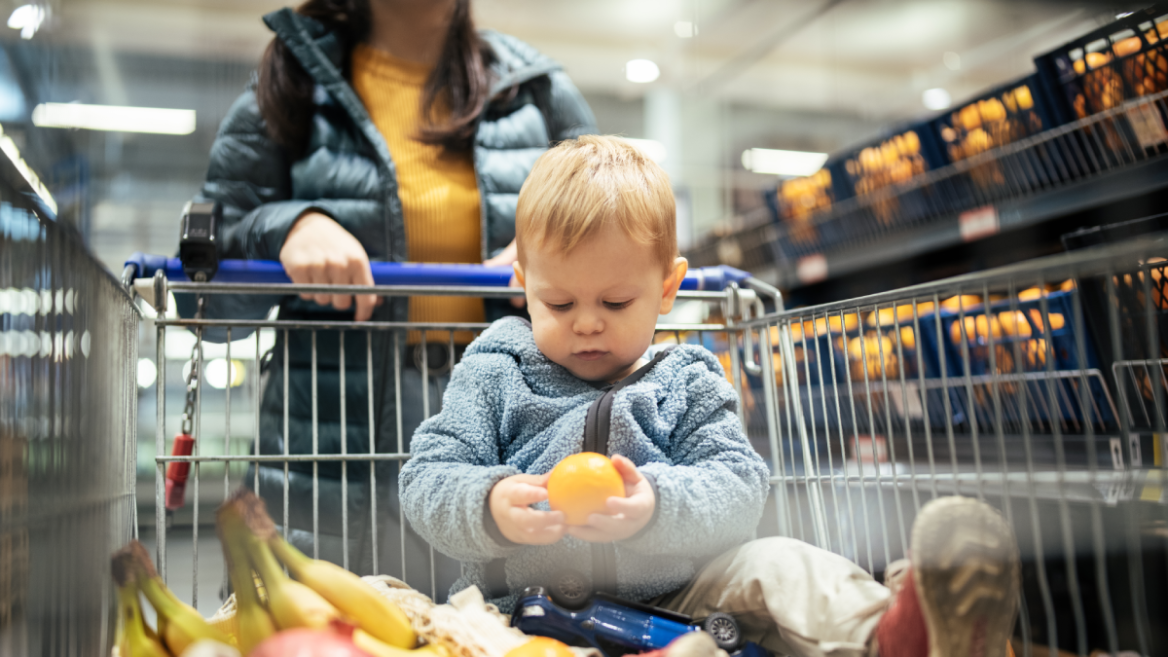 Mother and her young son buy fresh fruit at the supermarket.