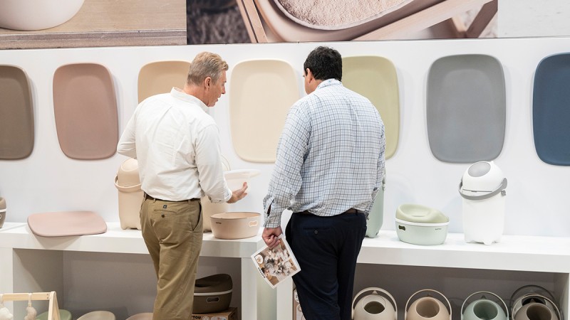 Two adults are talking in a store displaying various child-friendly bicycles and scooters. The image is themed “Discover Kind + Jugend”.