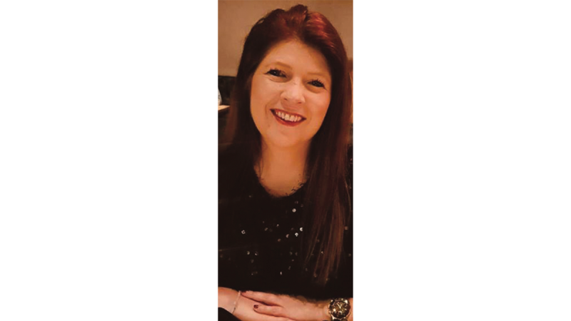 Person with long straight hair wearing a black top with small shiny details and a large wristwatch on left wrist