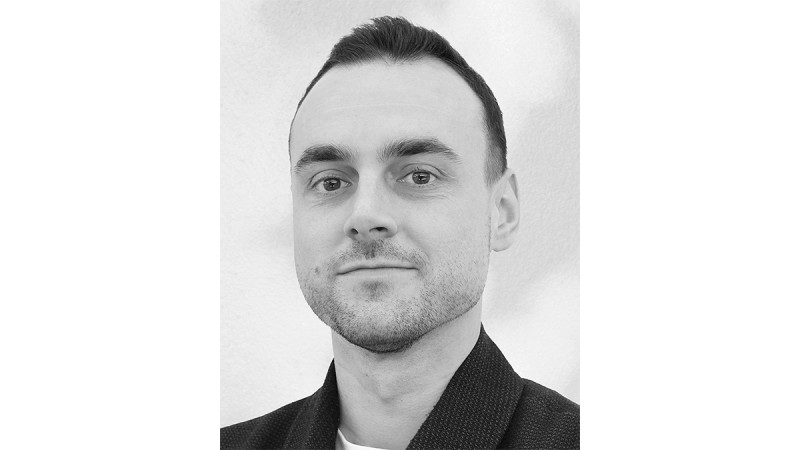 Portrait of a man with short hair, light beard, and neutral expression in black and white.