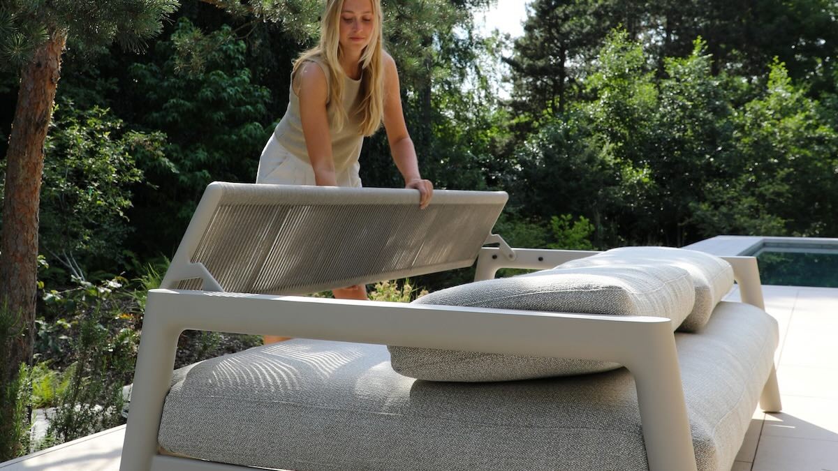 Frau wandelt die Sitzfläche eines Outdoorsofas in Liegefläche um