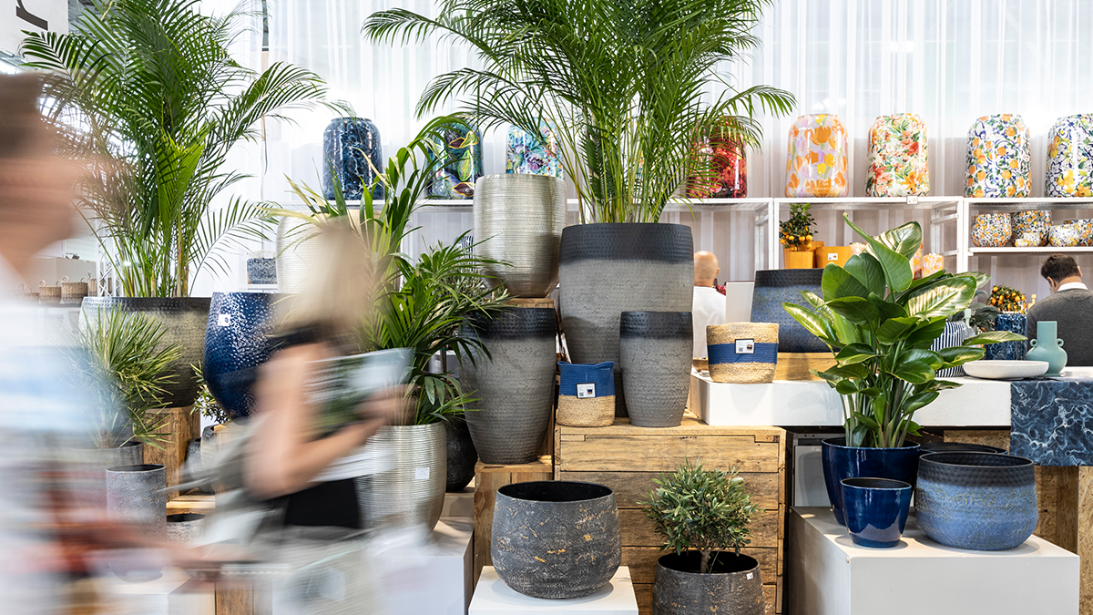 People sit at a table in front of a hanging construction of green plants and talk