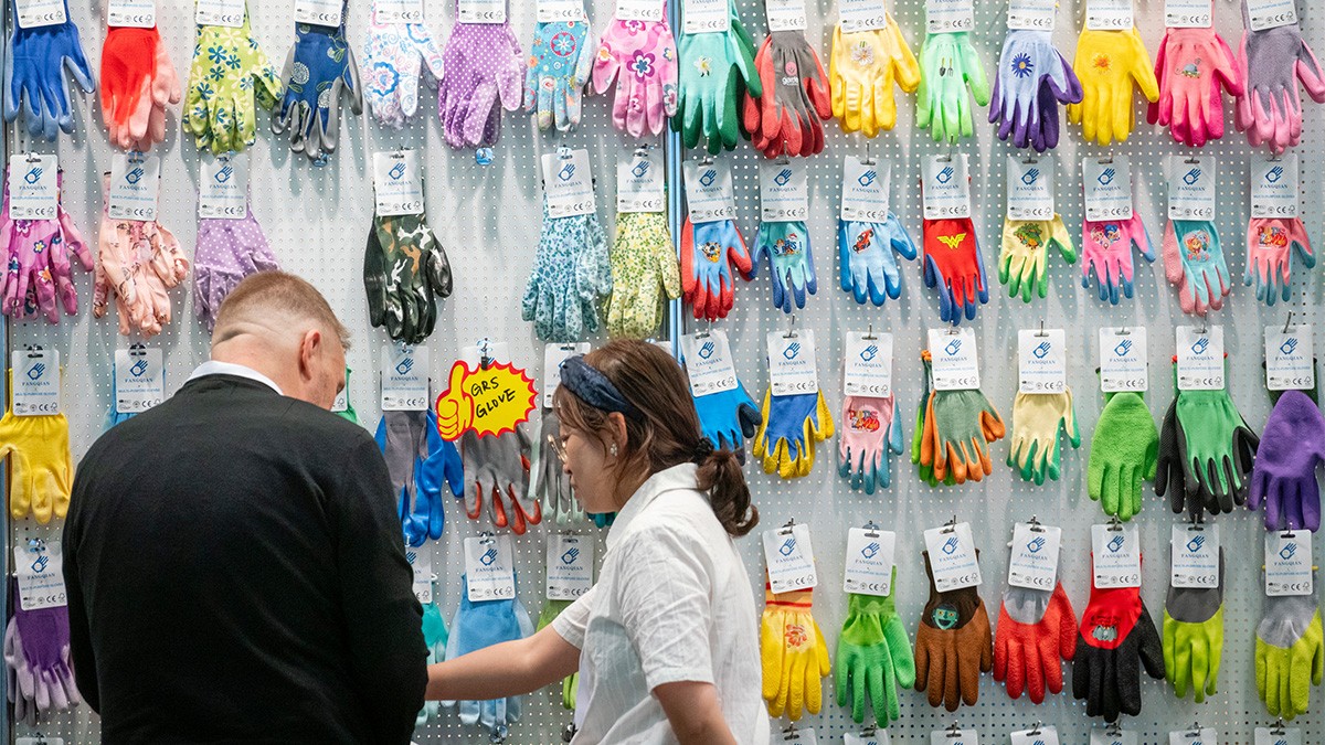 Bunte Gartenhandschuhe an einer Wand, zwei Personen davor.