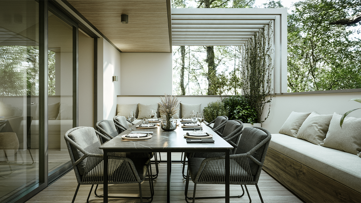 Modern gedeckter Esstisch auf einer Terrasse mit Stühlen, Sitzbank, Kissen und viel Grün im Hintergrund.